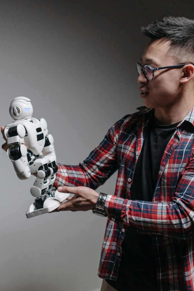 An adult man examines a humanoid robot against a gray background, exploring modern technology.